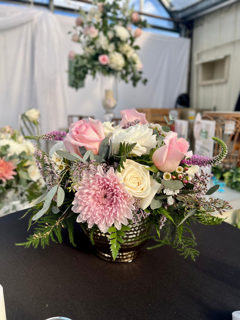 A variety of wedding floral arrangements, including lush centerpieces, elegant arch decor, free-standing ground installations, and delicate table accents. Featuring roses, peonies, wildflowers, and greenery, complemented by candles and soft lighting for a romantic ambiance.