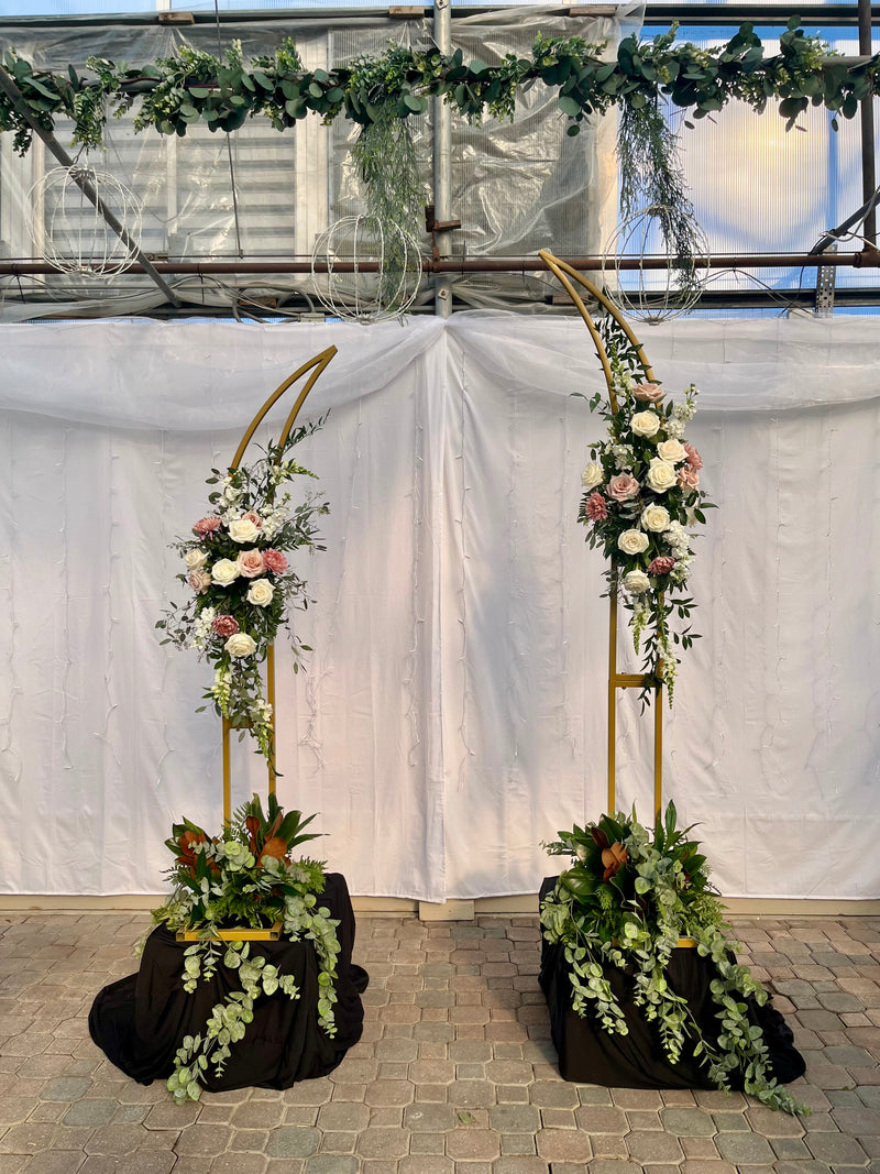 A variety of wedding floral arrangements, including lush centerpieces, elegant arch decor, free-standing ground installations, and delicate table accents. Featuring roses, peonies, wildflowers, and greenery, complemented by candles and soft lighting for a romantic ambiance.