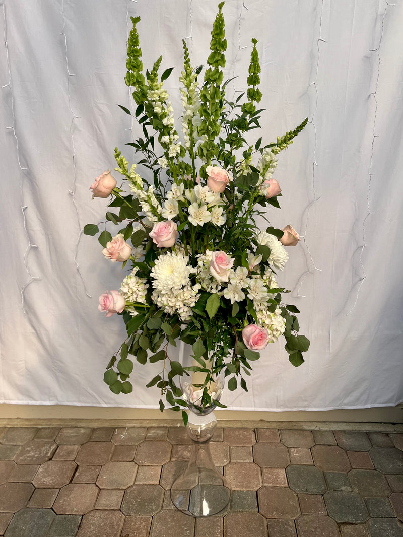 A variety of wedding floral arrangements, including lush centerpieces, elegant arch decor, free-standing ground installations, and delicate table accents. Featuring roses, peonies, wildflowers, and greenery, complemented by candles and soft lighting for a romantic ambiance.