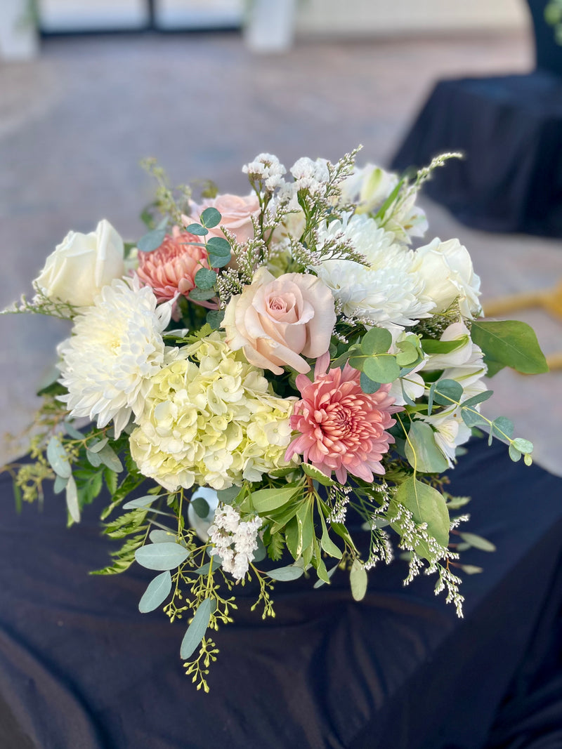 A variety of wedding floral arrangements, including lush centerpieces, elegant arch decor, free-standing ground installations, and delicate table accents. Featuring roses, peonies, wildflowers, and greenery, complemented by candles and soft lighting for a romantic ambiance.