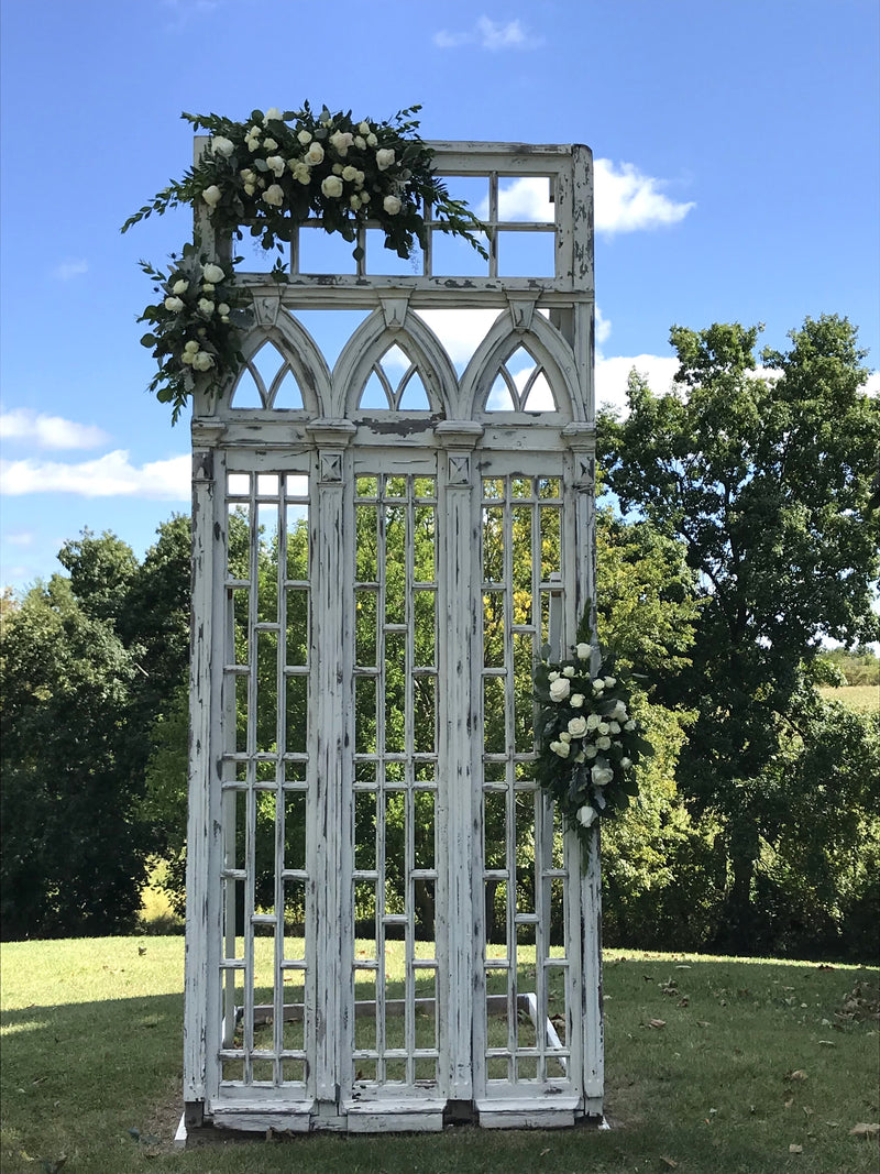 A variety of wedding floral arrangements, including lush centerpieces, elegant arch decor, free-standing ground installations, and delicate table accents. Featuring roses, peonies, wildflowers, and greenery, complemented by candles and soft lighting for a romantic ambiance.